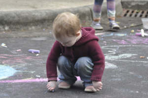 Child drawing with chalk on the pavement during Prayer Chain for the Earth