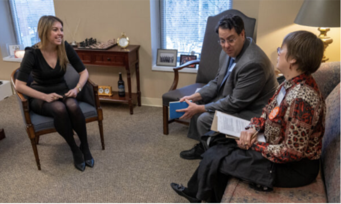 Three people sitting in representative’s office: male representative, female admin, and female constituent